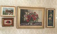 Photo of five framed needlepoint and floral artworks on wall, showing variety of sizes and styles.