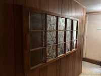 Front view of the large wooden framed window-pane mirror mounted on a wood-paneled wall.