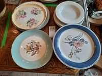 Group of decorative and everyday plates including floral and bird designs with pastel and blue rims