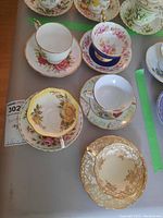 Five teacups with their matching saucers, showing different floral patterns and gold trim detail