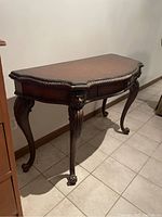 Side perspective of the carved Chippendale-style console table showing curved legs, ball-and-claw feet and lion head carvings on legs.
