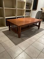 Angled side view of rectangular wooden coffee table showing vertical slat sides and lower shelf.