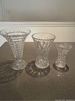 Photo of three fluted crystal vases of different sizes arranged side by side on a countertop.
