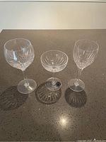 Photo of three vintage crystal wine glasses on a speckled countertop, showing clear etched starburst designs, two wine glasses and one coupe glass.