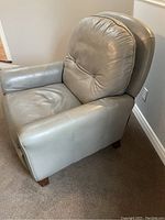 Leather recliner chair viewed from side showing armrest, seat cushion, and leather upholstery in good condition.