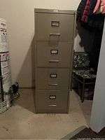 Front view of the four drawer metal filing cabinet in olive green, showing four drawers with label holders and recessed handles.