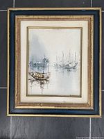 Framed vintage oil painting showing a maritime scene with boats in water and a misty atmosphere.