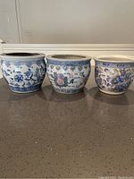 Three Chinese-style ceramic plant pots with blue and white floral patterns, different shapes and sizes, shown side by side.
