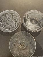 Top view of three cut-glass cake stands highlighting etched floral and geometric patterns on clear glass surfaces.