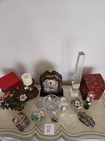 Overall photo showing all items on table including clock, glass dishes, candle, flowers, and decorative boxes.