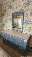 Full view of dresser with attached mirror against floral wallpaper