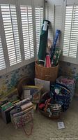 Full view of collection showing rolls of wrapping paper, wicker basket, gift bags, tissue paper and some boxes stacked on the floor by window.