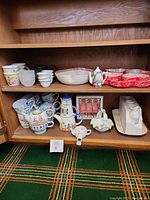 Photo of shelf with various tea and coffee sets, cups, serving dishes, and egg cups.