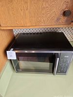 Closed view of Toshiba microwave showing black top and stainless front with handle and digital control panel.
