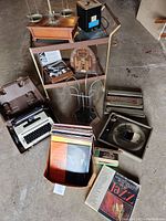 Photo showing overall lot with jeweler's scale, typewriter, vinyl records box, metal rack, radio, and Batt-Tronic watch press set.