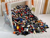 Large translucent plastic bin overflowing with mixed Lego pieces in varied colors and shapes.