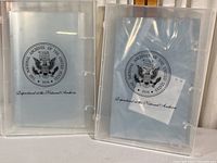 Two translucent polyvinyl archival storage boxes with the National Archives seal.