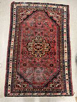Full view of red area rug laid flat showing overall pattern and wear