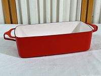 Front angle view showing red enamel exterior and right handle of the Dansk casserole dish.
