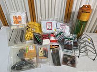 Photo showing assortment of gun cleaning items including packs of cleaning patches, yellow gloves, green cleaning tools, and a gray metal rack