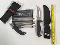 Both cutting tools displayed with blades, pouches, and measuring tape showing sizes