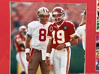 Central close-up of 8x10 color photo of Steve Young (#8 49ers) and Joe Montana (#19 Chiefs) standing on the field in uniform.