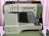Side view of the Elna sewing machine showing brand name and overall design in green and white color.