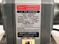 Close-up of the label on the bench grinder indicating 1/2 HP, model 397.1949, electrical specifications, and brand information.