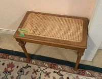 Full side view of antique wooden table with wicker inset top on a patterned rug.