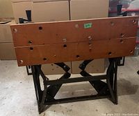 Collapsible workbench in folded position showing wooden top surface and metal frame base