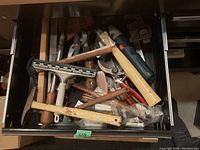 Drawer showing various types of hand tools including pruning shears, a hammer, a squeegee, pliers and a cordless rotary tool.