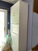 Full view of white metal filing cabinet showing tall, rectangular shape with drawers and cabinets.