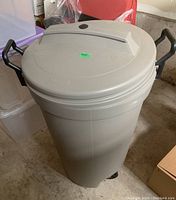 Top view of gray Rubbermaid Roughneck garbage can with lid and handles.