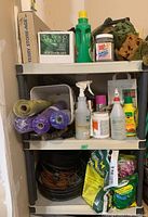 Shelf with rolls of mesh fabric, spray bottles, chemical bottles, sponge, and storage boxes