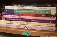 Stack of seven knitting and textile books on a wooden surface, titles clearly visible.