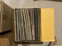 Cardboard box packed with approximately fifty vinyl records in paper and cardboard sleeves