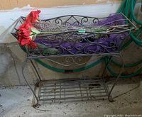 Full view of the metal plant stand with the top basket loaded with silk flowers and decorative elements, showing scrollwork design.