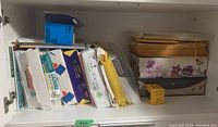 Shelf containing stacked unopened and partially used packs of 8.5 x 11 paper and envelopes