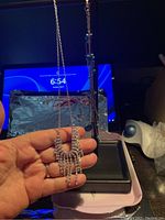 Silver-toned necklace with rhinestone dangles held in hand, showing details clearly