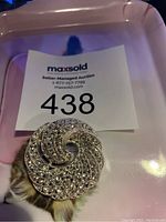 Front view of brooch displaying swirling rhinestone pattern