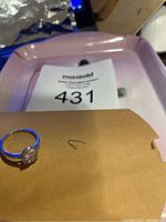 Ring placed on a pink tray with MaxSold lot number in background.