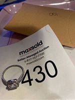 Photo of the sterling silver ring placed next to the auction card and packaging.