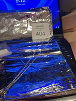 Full shot of sterling silver necklace with pendant lying on foil background showing chain and pendant shape.