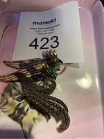 Front of vintage bird brooch showing intricate feather detail and color accents