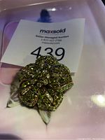 Photo of the vintage floral brooch featuring intricate gold-tone metal and green rhinestones on flower petals.