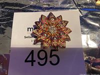 Front view of vintage floral brooch with red enamel and rhinestones.