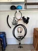 Lot contents photo showing helmets, tires, locks, shoes, pump against a garage wall.