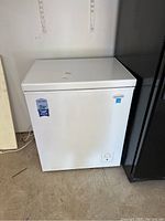 Front view of white Marathon chest freezer with warranty sticker, power cord visible.