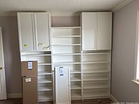Full view of three assembled white shelving modules flanked by two upper cabinet modules with closed doors