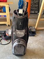 Front view of black and gray PING golf bag showing multiple compartments and pockets.
